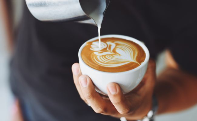 Cappuccino latte art Muster Barista mit Milchkanne